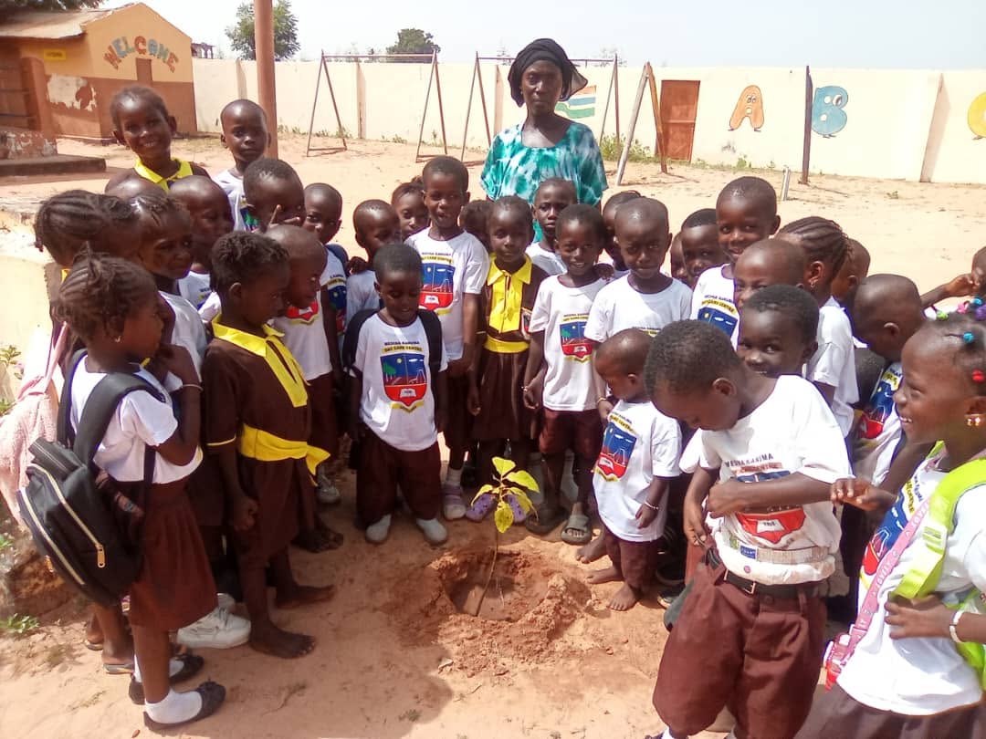 Pupils and teachers forming a circle around a newly planted tree