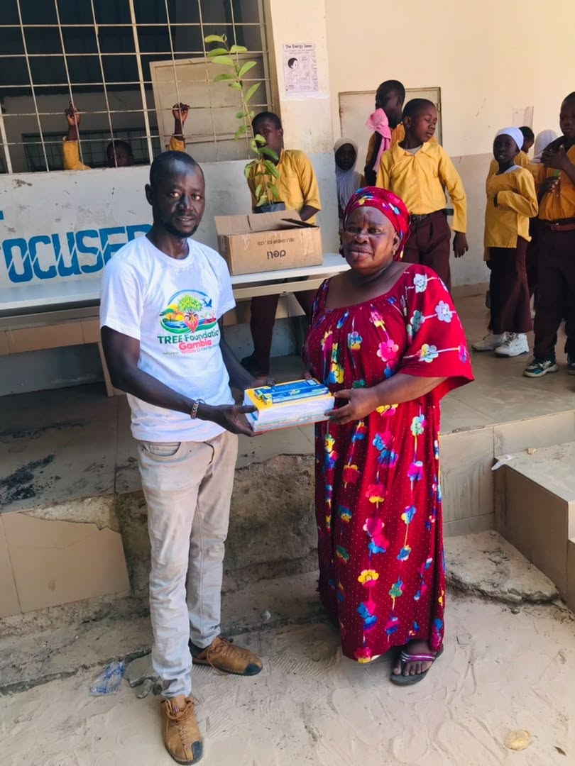 A TREE Foundation team member handing learning materials to a school leader